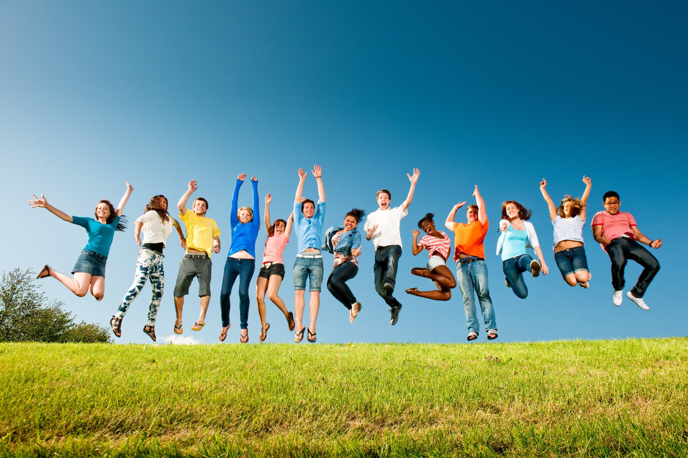 Students jumping in the air on a sunny hillside