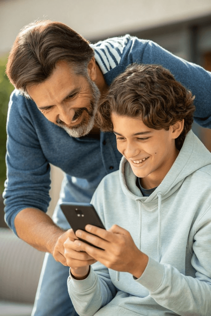 Father and teenage son looking at a phone together